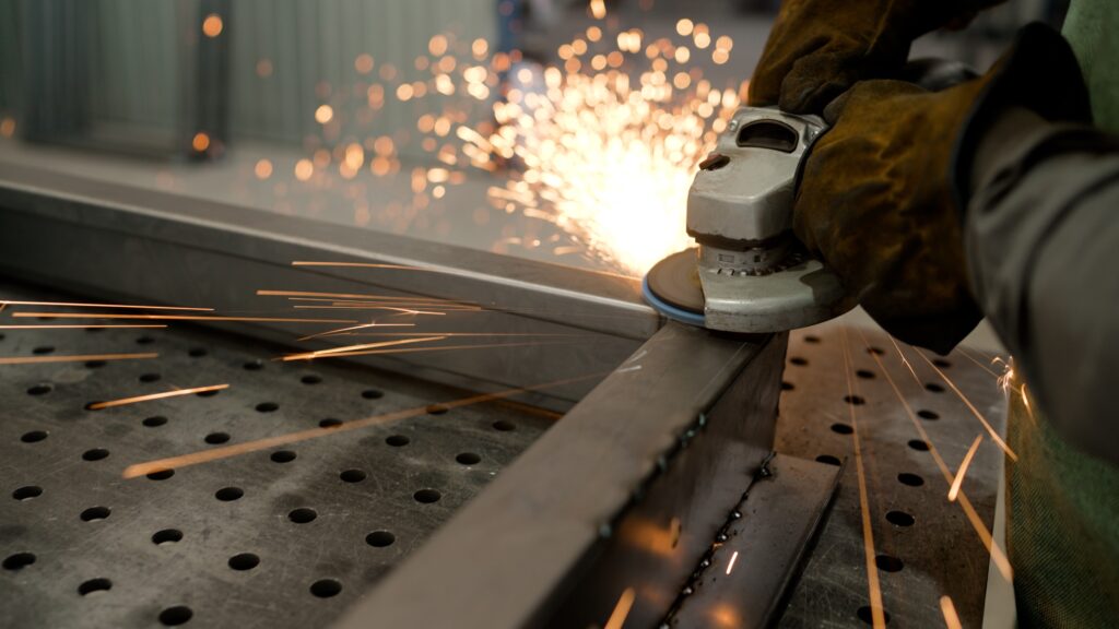 Professional,metal,worker,generating,bright,sparks,while,grinding,perforated,steel